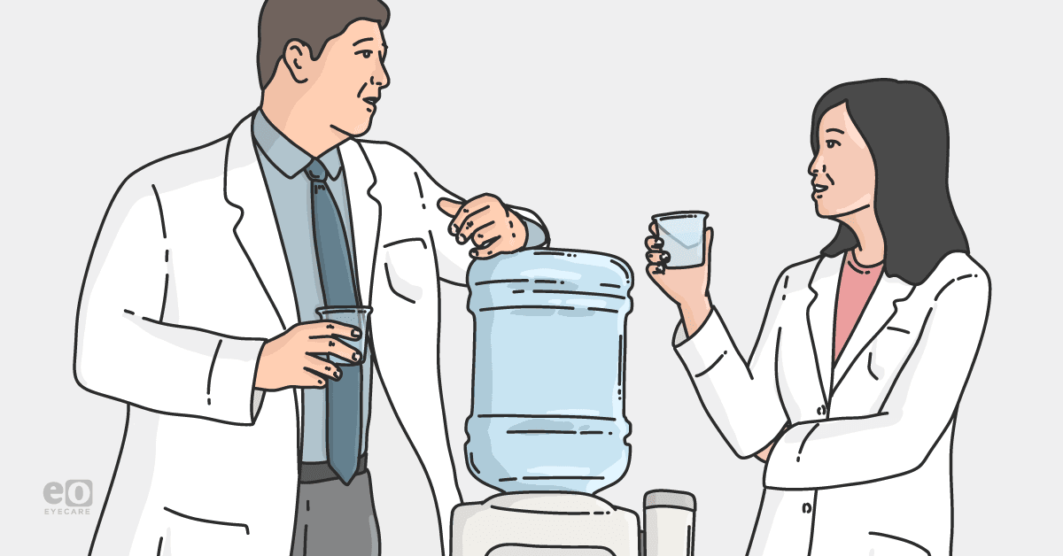 Image of two eyecare practitioners chatting in front of a water cooler to represent how to settle conflicts in eyecare practices.