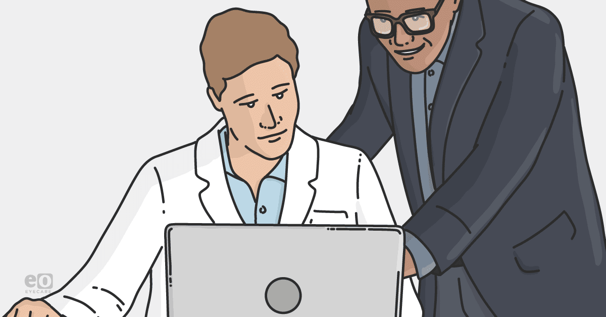 Image of an optometrist and practice manager having a conversation while looking at a laptop.
