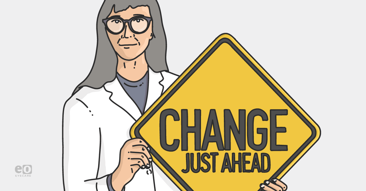 Image of an eye doctor in a labcoat holding up a yellow sign that says change just ahead to represent how eyecare practices can effectively implement change for sustained growth.